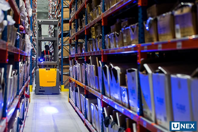 Man in heavy equipment navigating warehouse shelving and dynamic storage